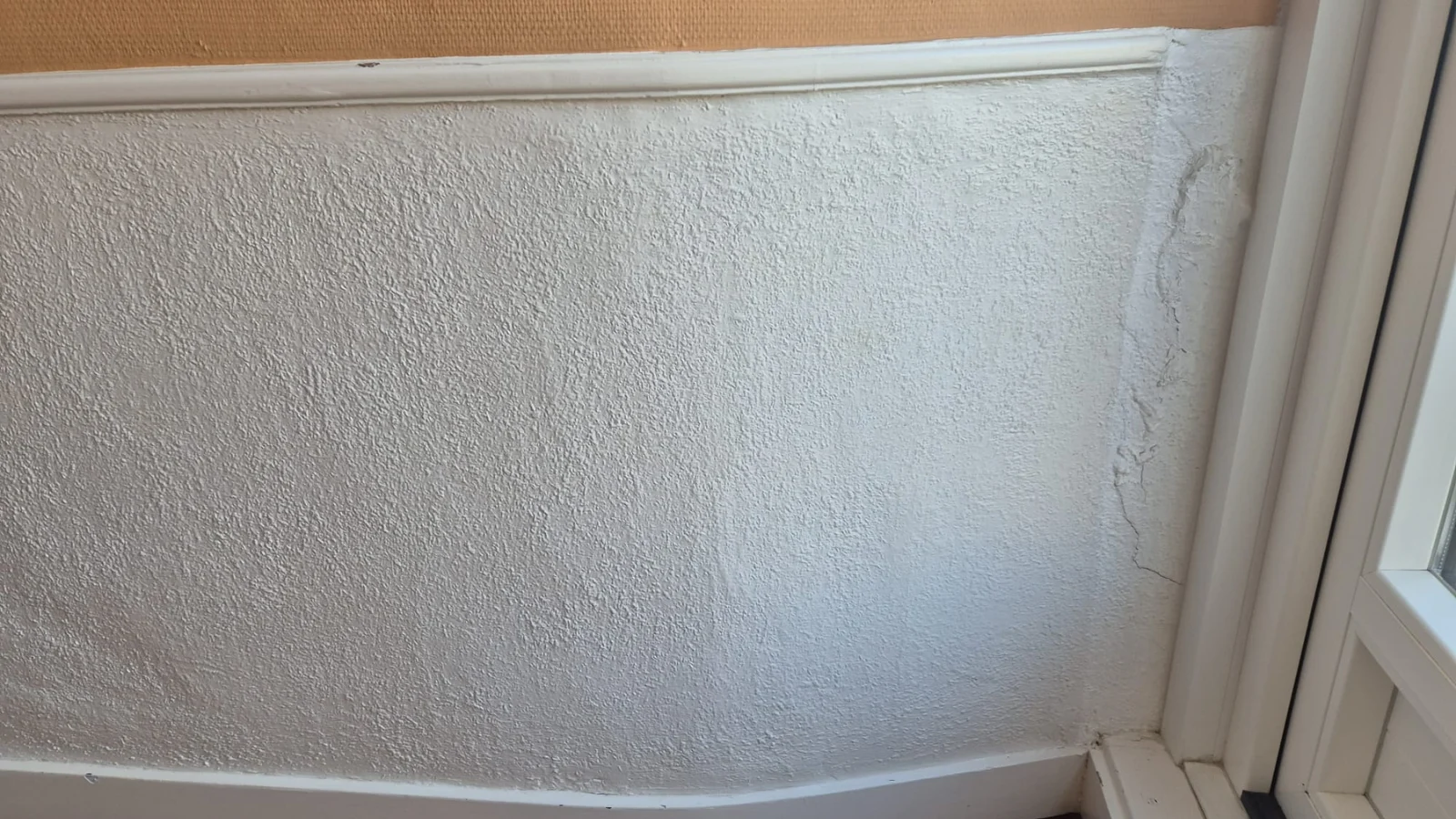 Peeling paint on wall and window corner.