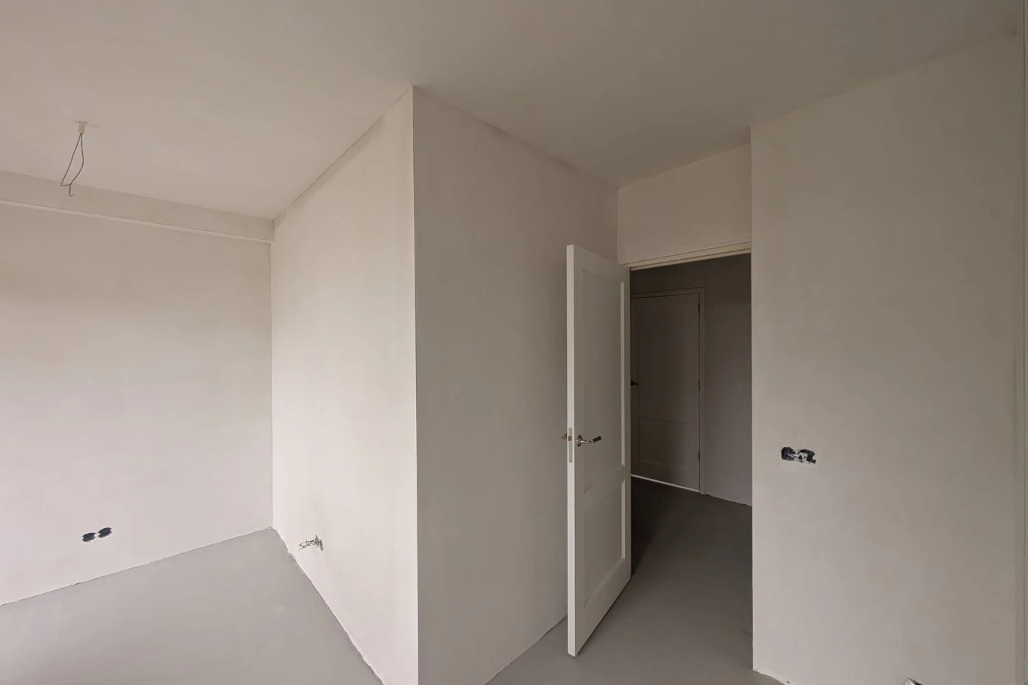 Empty room with an open door and white walls.
