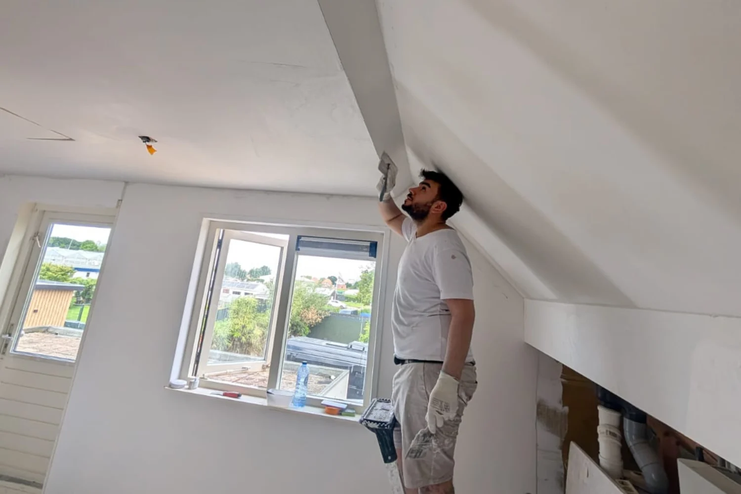 Man plasters ceiling in attic room